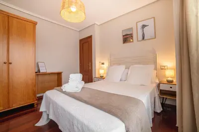 a bedroom with a large bed with white sheets at Pensión O Camiño in Sarria