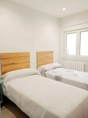 three beds in a room with white walls and windows at A Ledicia de Ana in Viveiro