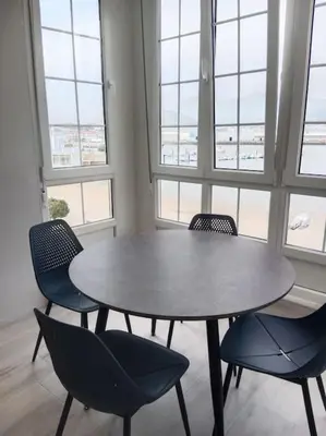 a table and chairs in a room with windows at A Ledicia de Ana in Viveiro