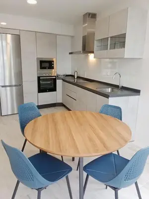 a kitchen with a wooden table and blue chairs at A Ledicia de Ana in Viveiro