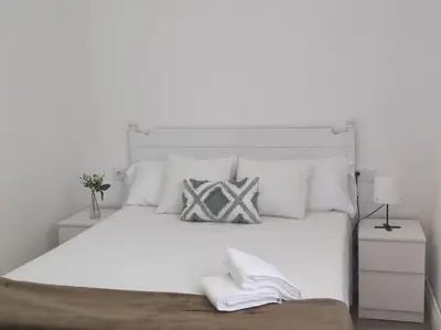 a white bedroom with a large white bed with pillows at Casa Dina II. in Carballino