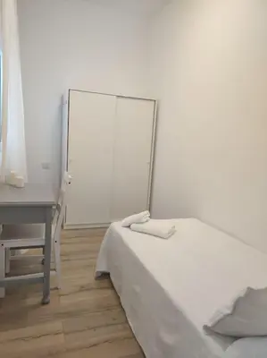 a white bedroom with a bed and a desk at Casa Dina II. in Carballino