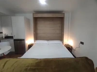 a bedroom with a large bed with a wooden headboard at 1A. Estudio para disfrutar y tapear en Ourense in Ourense