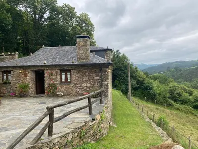 a stone house on a hill with a fence at Casa da Costa de Sueiro in Sueiro