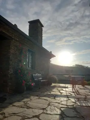 a stone house with the sun setting behind it at Casa da Costa de Sueiro in Sueiro