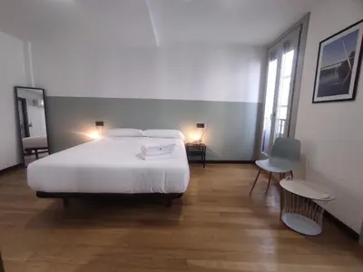 a bedroom with a large white bed and a chair at 2. Luminoso y único en la mejor zona gastronómica in Ourense