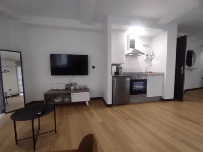 a living room with a television and a table and a kitchen at 2. Luminoso y único en la mejor zona gastronómica in Ourense