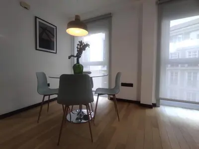 a dining room table with chairs and a vase with flowers on it at 2. Luminoso y único en la mejor zona gastronómica in Ourense