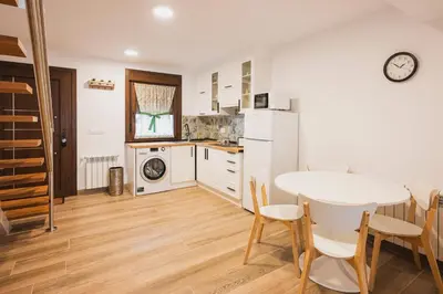 a kitchen with a table and a white refrigerator at Apartamentos Luis in Arzúa