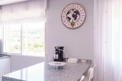 a kitchen with a clock on the wall and a counter at Antoxos Sacra Home II in Chantada