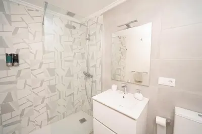a white bathroom with a shower and a sink at Antoxos Sacra Home II in Chantada