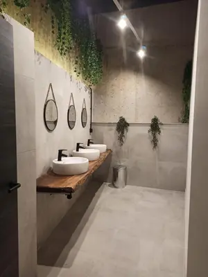 a bathroom with three sinks and plants on the wall at Albergue HR in Sarria