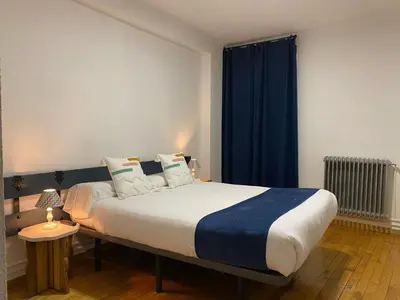 a bedroom with a large bed with blue curtains at Hostal La Trucha Sanabria in Puebla de Sanabria