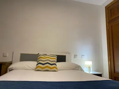 a bed with a yellow and blue striped pillow on it at Hostal La Trucha Sanabria in Puebla de Sanabria