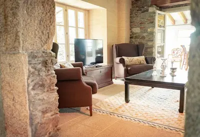 a living room with a tv and chairs and a table at Villa Los Magnolios in Paderne
