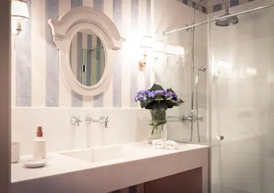 a bathroom with a sink and a vase of purple flowers at Villa Los Magnolios in Paderne