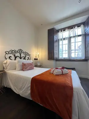 a bedroom with a large bed with an orange blanket on it at CLAREN´S BOUTIQUE ROOMS in Cangas del Narcea