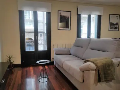 a living room with a couch and a door at 1A. Disfruta de su balcón sobre el casco viejo. in Ourense