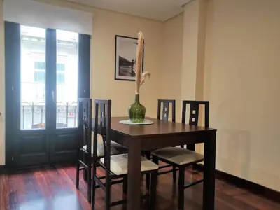 a dining room table with chairs and a vase on it at 1A. Disfruta de su balcón sobre el casco viejo. in Ourense