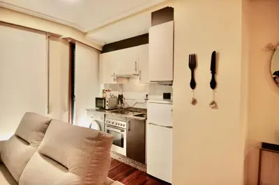 a kitchen with white cabinets and a chair and utensils at 1F.Céntrico y tranquilo en la ciudad de las Burgas in Ourense