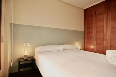 a bedroom with a large white bed and a night stand at 1F.Céntrico y tranquilo en la ciudad de las Burgas in Ourense