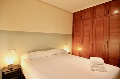a bedroom with a white bed and wooden cabinets at 1F.Céntrico y tranquilo en la ciudad de las Burgas in Ourense