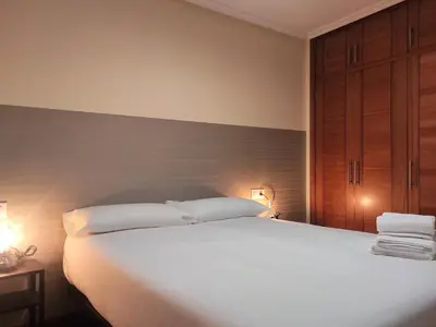 a bedroom with a large white bed with two pillows at 2A. Dos dormitorios y balcones en el casco viejo. in Ourense