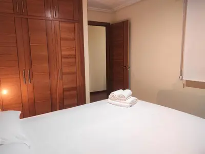 a bedroom with a white bed and a closet at 2A. Dos dormitorios y balcones en el casco viejo. in Ourense