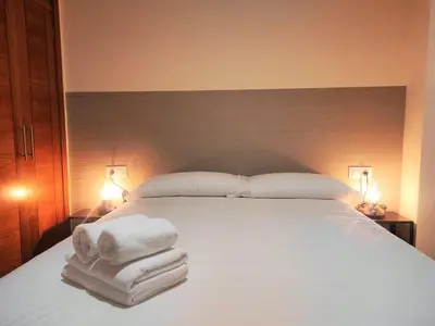 a bedroom with a large white bed with towels on it at 2A. Dos dormitorios y balcones en el casco viejo. in Ourense