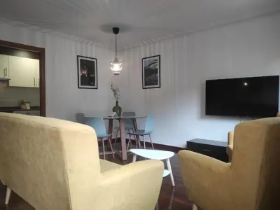 a living room with chairs and a tv and a table at 2D.Tres dormitorios y balcón con vistas al parque in Ourense
