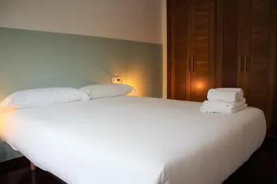a bedroom with a white bed with towels on it at 2D.Tres dormitorios y balcón con vistas al parque in Ourense