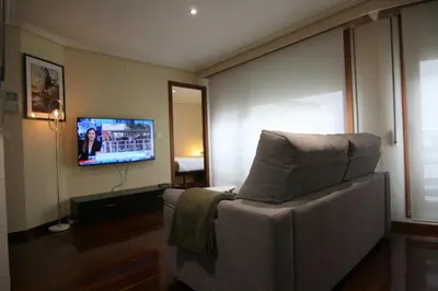 a living room with a chair and a flat screen tv at 3B.Descansa y disfruta en el corazón de las Burgas in Ourense