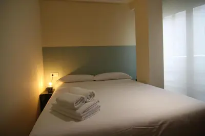 a bedroom with a white bed with towels on it at 3B.Descansa y disfruta en el corazón de las Burgas in Ourense