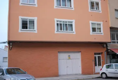 an orange building with a white door and cars parked in front at Casa Fernando in Burela de Cabo