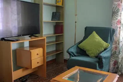 a living room with a chair and a flat screen tv at Casa Fernando in Burela de Cabo