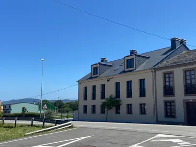 a white building with black windows on a street at O TEU SITIO in Ribadeo