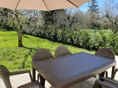 a table with chairs and an umbrella on a patio at LA CASA DEL RÍO - A 13 kilómetros de Santiago in Sigüeiro