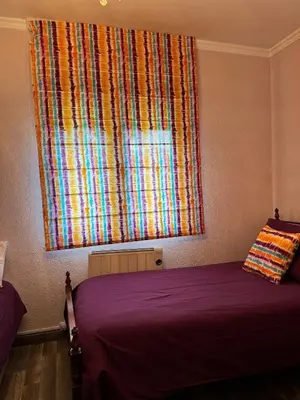 a bedroom with a window with a colorful curtain at casa carmiña in Ourense
