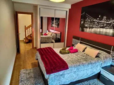 a bedroom with a bed with a red wall at Casa Nicolas in Chantada