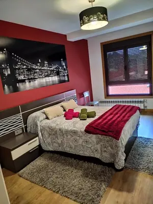 a bedroom with a large bed with a red wall at Casa Nicolas in Chantada
