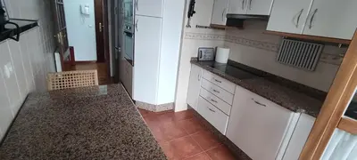 a kitchen with white cabinets and a tile floor at Apartamento Laguna in Ribadeo