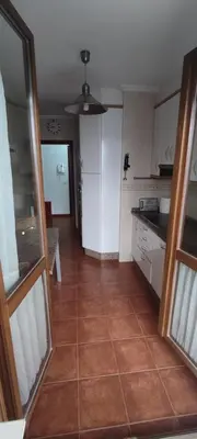 a kitchen with white cabinets and a tile floor at Apartamento Laguna in Ribadeo