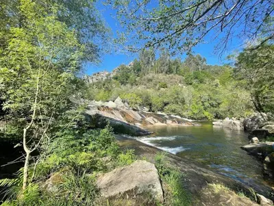 a river with rocks and trees next to a mountain at Molino cascada de caldas de reyes in Caldas de Reis