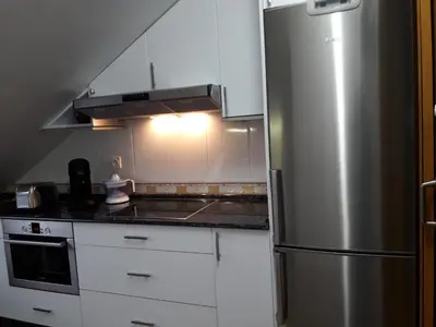 a kitchen with white cabinets and a stainless steel refrigerator at TEMPLE in Ponferrada