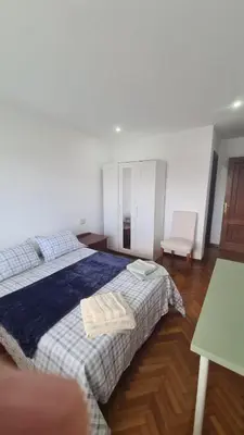 a bedroom with a large bed and a chair at San Roque Lucus Confort in Lugo