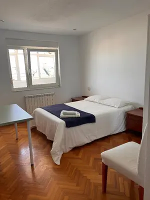 a bedroom with two beds and a table and a window at San Roque Lucus Confort in Lugo