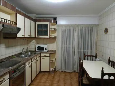 a kitchen with a sink and a table with a microwave at Piso Doniz in Ourense
