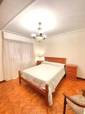 a bedroom with a bed and a table and a ceiling at Piso Doniz in Ourense