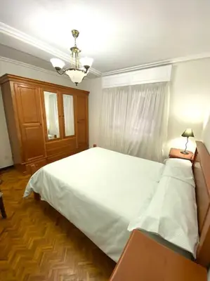 a bedroom with a large white bed and a chandelier at Piso Doniz in Ourense