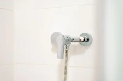 a shower head in a white tiled bathroom at Apartamento Carmiña in Puentedeume